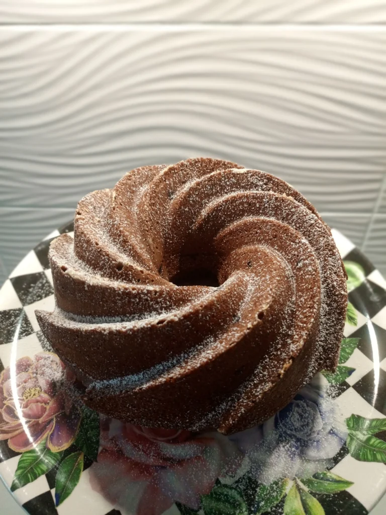 A bundt cake dusted with sugar on a patterned plate